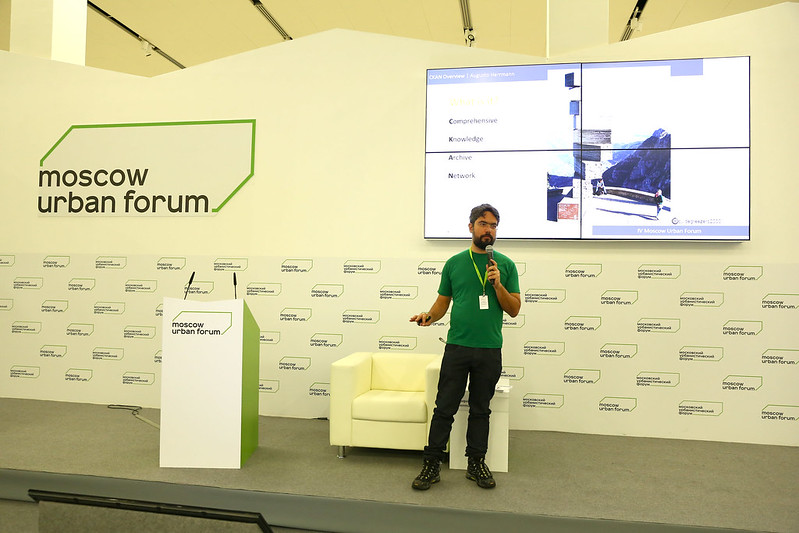 Augusto with a microphone at the stage of the IV Moscow Urban Forum, presenting CKAN