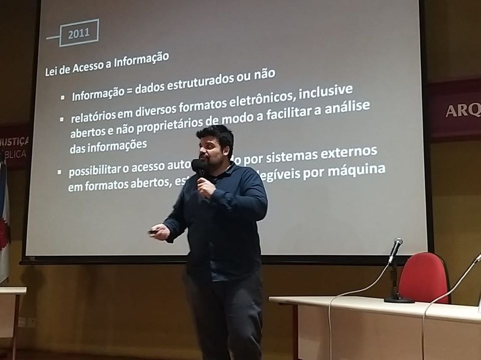 Otávio Neves speaking. Behind him, a slide conveying information about the Access to Information Law. 2011. Access to Information Law. Information: structured data or not. Reports in electronic formats, including open and non proprietary ones. Make possible automated access by external systems.
