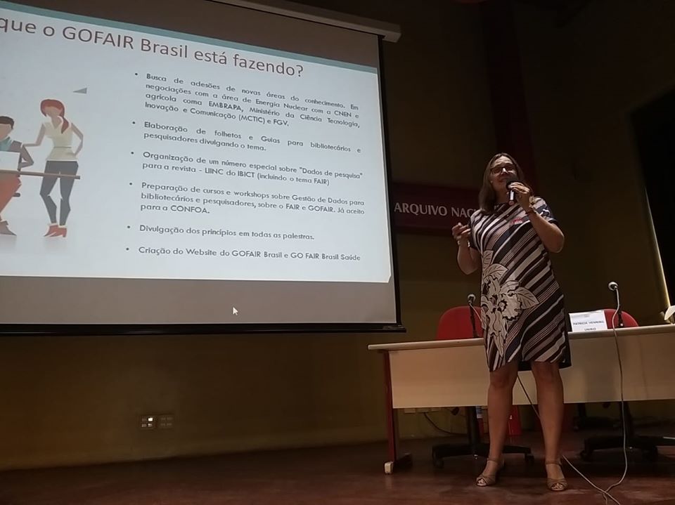 Patricia Henning speaks in the auditorium of the National Archives for the Open Data Day 2020. Behind her, the slides read 'what is GOFAIR Brazil doing'.