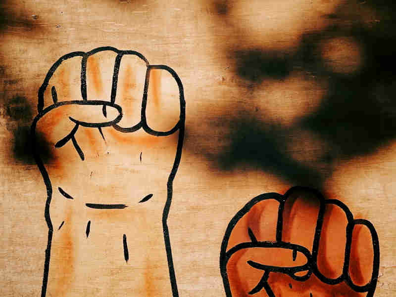 Photo of graffiti representing resistance through clenched fists and raised arms.
